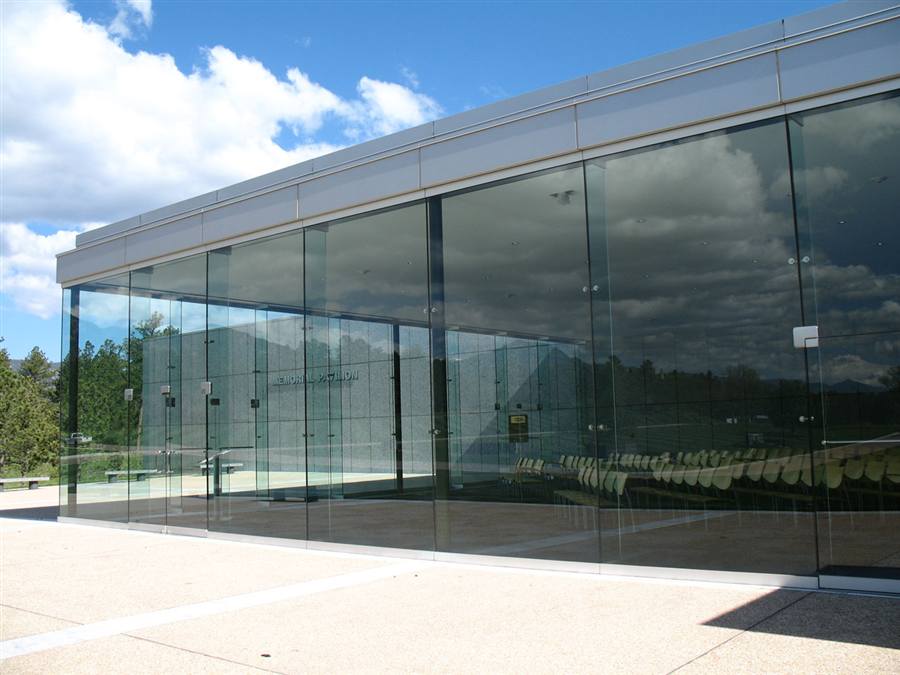 Memorial Pavilion — all-glass walls reflecting sky and pines